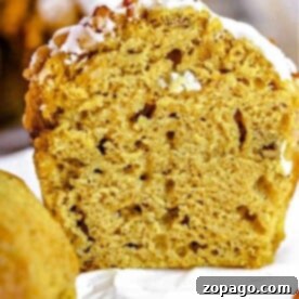 Close-up of a sliced mini pumpkin banana muffin topped with white icing, revealing a moist and fluffy texture.