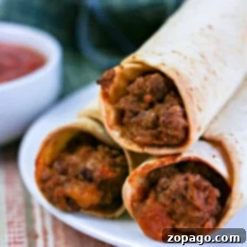 Crispy Air Fryer Flautas 9 Three crispy ninja foodi air fryer flautas rest on a white plate with a side of salsa, placed on a striped cloth.