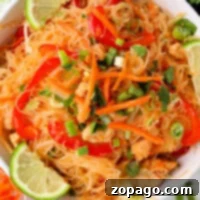 Quick Instant Pot Pad Thai 6 A bowl of rice noodles with chicken, carrots, bell peppers, and green onions, perfectly capturing the flavors of instant pot Pad Thai, garnished with fresh lime wedges.