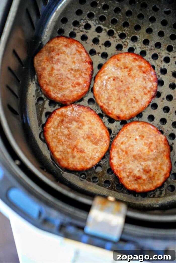 Easy Air Fryer Sausage Patties 5 Four cooked sausage patties in an air fryer basket, showing just how easy it is to make delicious sausage patties in air fryer for a quick breakfast.