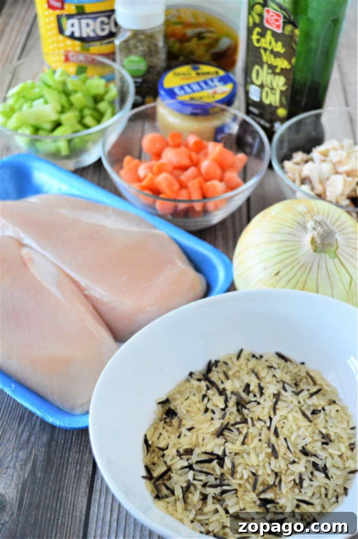 Comforting Instant Pot Chicken and Rice Soup 3 Essential ingredients for a homemade Instant Pot Chicken Rice Soup, including raw chicken, wild rice, celery, carrots, onion, chicken broth, olive oil, and corn starch for thickening.