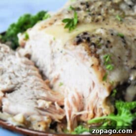 Frozen pork roast cooked in an Instant Pot with herbs, sliced and served on a plate garnished with fresh parsley.