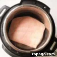Crispy Instant Pot Pork Belly Bites 5 A square piece of pork belly in an Instant Pot, submerged in water.