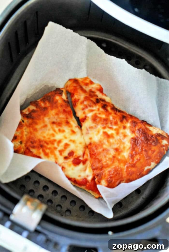 Air Fryer Pizza Reheat: Crispy Perfection 2 How-to-Reheat-Pizza-in-Air-Fryer - A golden-brown pizza slice with melted cheese in an air fryer basket, ready to be enjoyed.