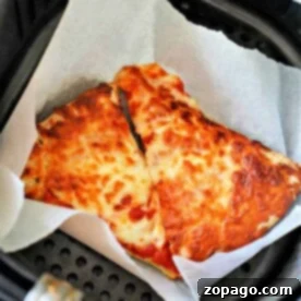 How-to-Reheat-Pizza-in-Air-Fryer - A close-up of a perfectly reheated pizza slice in an air fryer basket, with crispy crust and bubbling cheese.