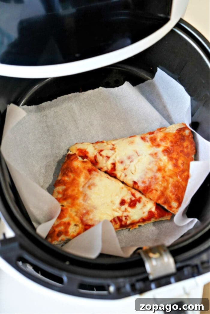Air Fryer Pizza Reheat: Crispy Perfection 6 reheating pizza in air fryer - A hand carefully placing two slices of pepperoni pizza into an air fryer basket lined with parchment paper.