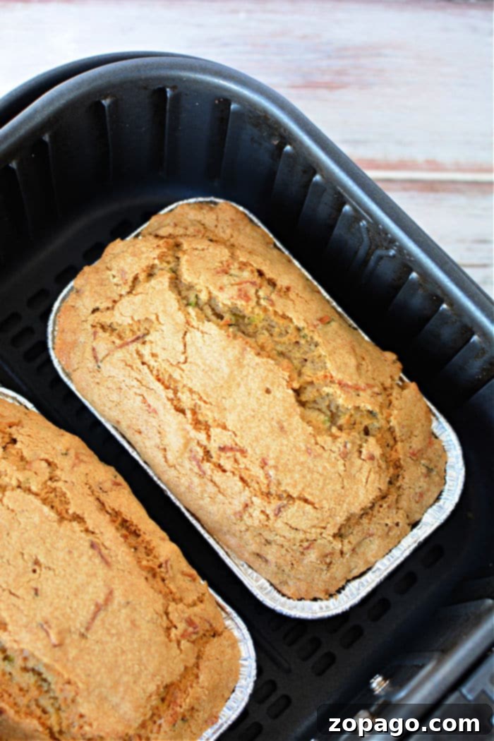Crispy Air Fryer Zucchini Loaf 2 Golden brown air fryer zucchini bread in a mini loaf pan, fresh from the air fryer.