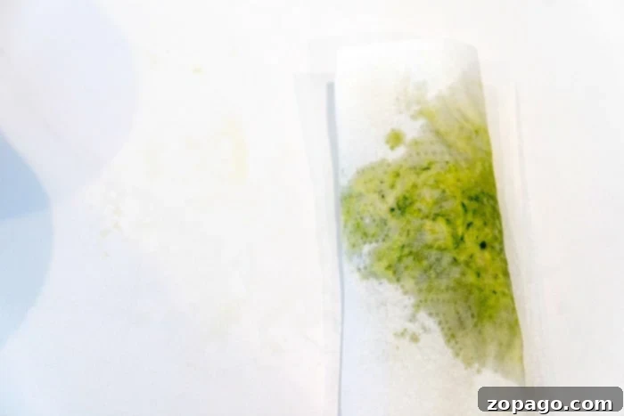 Crispy Air Fryer Zucchini Loaf 7 A sheet of folded paper towels absorbing the moisture of shredded zucchini to bake with.