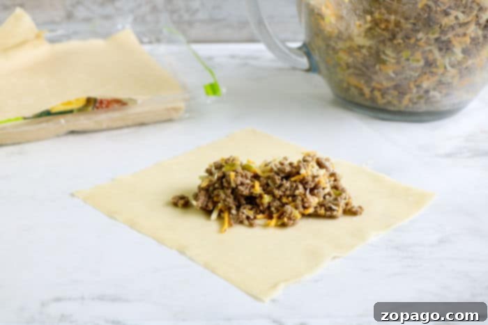Crispy Beef Egg Rolls 6 Freshly rolled egg rolls arranged on a cutting board, ready for cooking