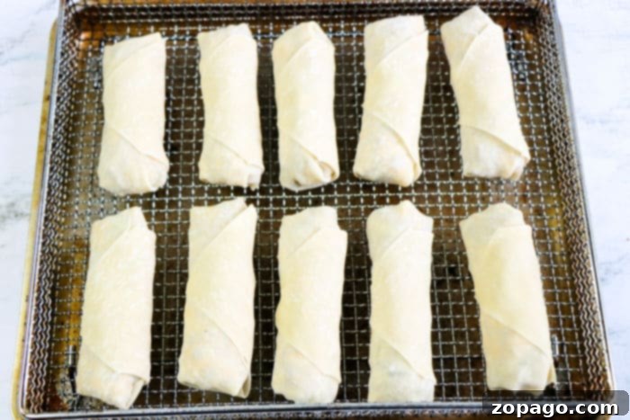 Crispy Beef Egg Rolls 7 Air Fryer ground beef egg rolls cooking in the air fryer basket, turning golden