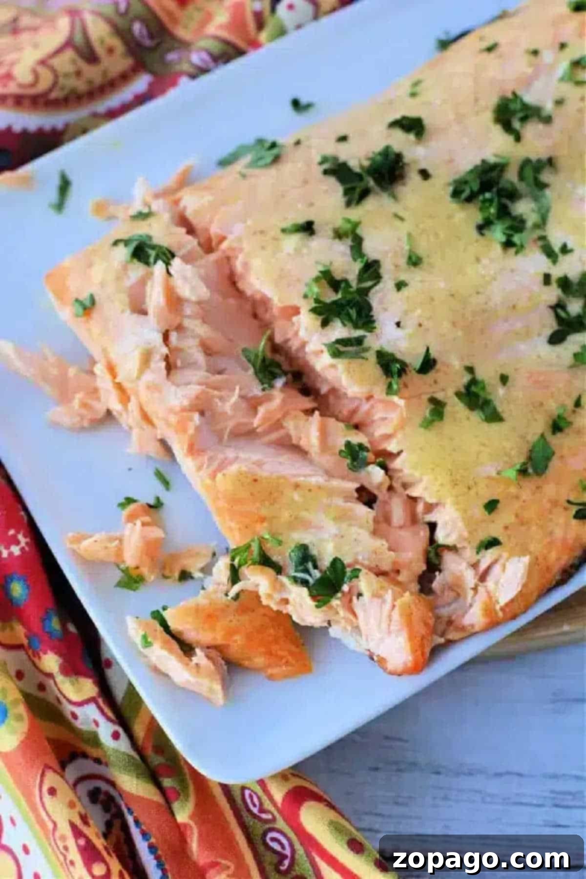 Perfect Air Fryer Frozen Salmon 2 Frozen salmon in air fryer, cooked to perfection and garnished with chopped herbs on a white plate, partially flaked.