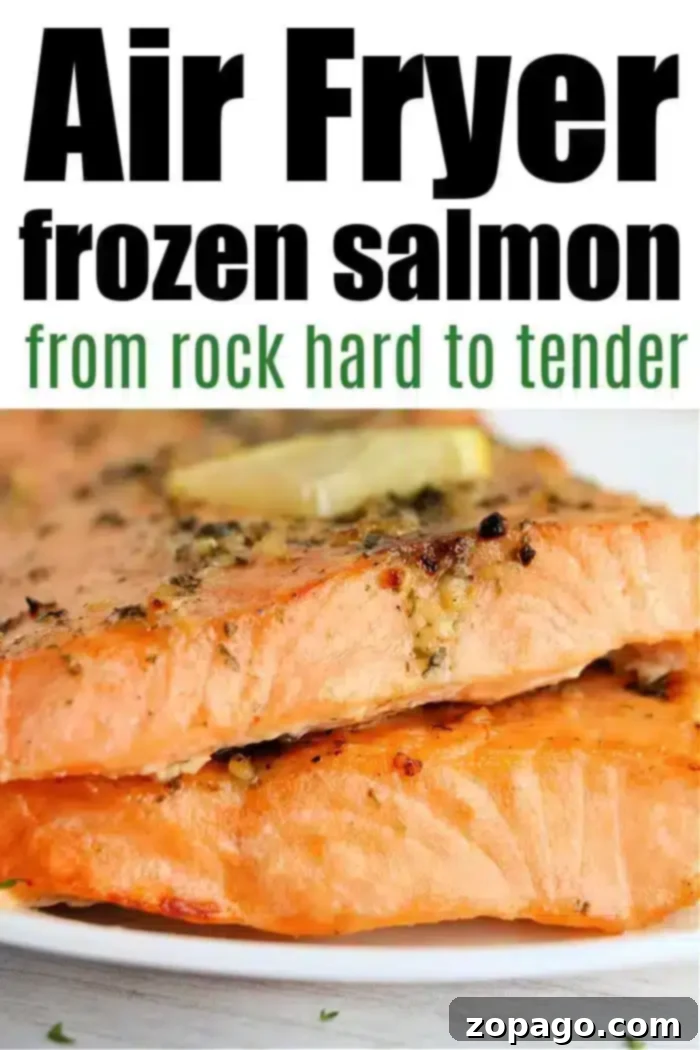 Perfect Air Fryer Frozen Salmon 9 Close-up of two cooked salmon fillets, seasoned with herbs and topped with a slice of butter on a white plate. Text at the top reads, "Frozen salmon in air fryer: from rock hard to tender.