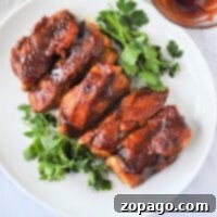 Country style pork ribs, tenderized in the Instant Pot, are glazed with sauce on a white plate, garnished with fresh parsley.