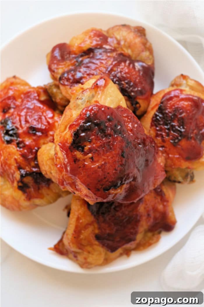 Perfect Air Fryer Frozen Chicken Thighs 2 Perfectly cooked frozen chicken thighs with barbecue sauce in an air fryer basket, ready to serve.