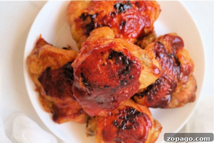 Perfect Air Fryer Frozen Chicken Thighs 8 Two juicy BBQ chicken thighs, air-fried to perfection, served on a plate with fresh parsley garnish.