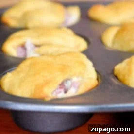 Reinvent Your Leftover Ham 4 Golden brown crescent roll sandwiches baked in a muffin tin, with filling visible at the edges—a perfect leftover ham recipe for easy, savory snacks.