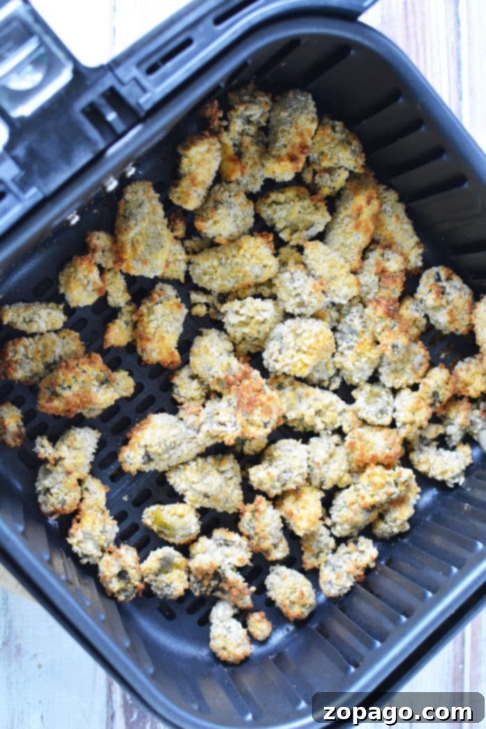 Crispy Air Fryer Oysters 6 Panko breaded oysters arranged in an air fryer basket, ready to cook.