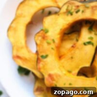 Sliced air fried acorn squash on a white plate, garnished with chopped herbs for a delightful flavor, reveals the magic of air fryer acorn squash.