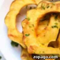 Sliced air fried acorn squash on a white plate, garnished with chopped herbs for a delightful flavor, reveals the magic of air fryer acorn squash.