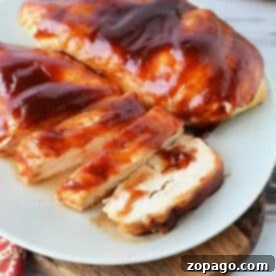 Juicy Air Fryer BBQ Chicken Breast 8 Air fryer BBQ chicken breast, sliced and coated in tangy barbecue sauce, served on a white plate atop a wooden board. A delicious and healthy air fryer recipe.