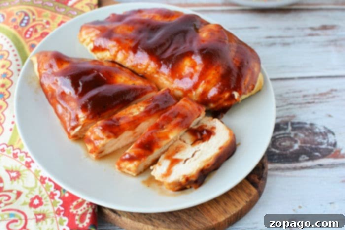 Juicy Air Fryer BBQ Chicken Breast 9 Sliced barbecue chicken breast on a white plate, showcasing its juicy interior and caramelized sauce. A quick and healthy air fryer meal.