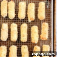Crispy Homemade Air Fryer Mozzarella Sticks 5 Homemade mozzarella sticks lined up on a wire rack, ready for the air fryer.