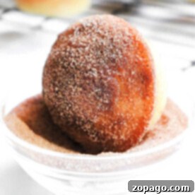 Donut Muffins 7 A delicious donut muffin being dipped into a bowl of cinnamon sugar, capturing the irresistible charm of classic donut muffins.