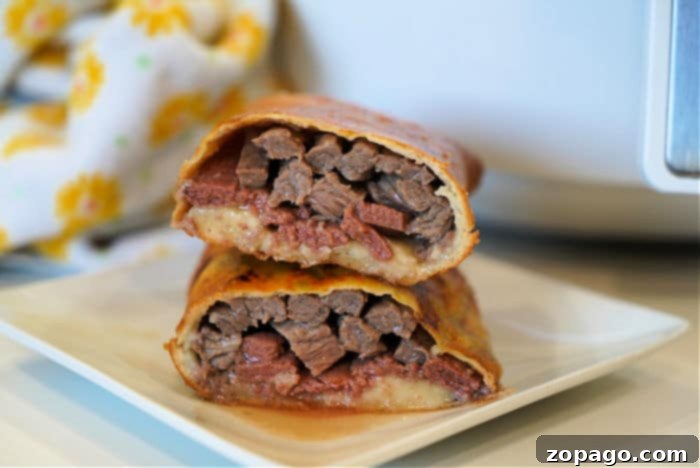 Crispy Air Fryer Beef Wellington Pockets 9 Two beef Wellington hot pockets on a plate with a side of dipping sauce.