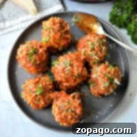 Easy Instant Pot Porcupine Meatballs 6 A plate with seven instant pot porcupine meatballs covered in tomato sauce and garnished with chopped herbs. A spoon rests on the plate, while a piece of cheese and parsley linger in the background.
