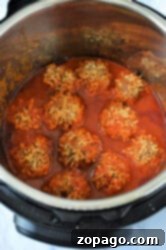 Easy Instant Pot Porcupine Meatballs 8 An Instant Pot filled with porcupine meatballs in a rich red tomato sauce. The meatballs, perfectly cooked, are partially submerged, allowing a glimpse of the seasoned sides and bottom of the cooker.
