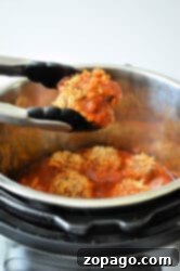 Easy Instant Pot Porcupine Meatballs 9 Tongs holding a portion of porcupine meatballs in front of an Instant Pot filled with stuffed peppers in tomato sauce. The dish consists of ground meat and rice in red sauce.