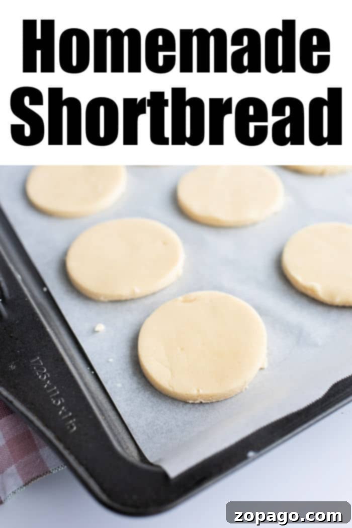 Effortless 3-Ingredient Shortbread 7 A rectangular baking tray showcasing a neat arrangement of unbaked, round homemade shortbread cookies on a sheet of parchment paper. The words 'Homemade Shortbread' are prominently displayed at the top, emphasizing the simple joy of baking.