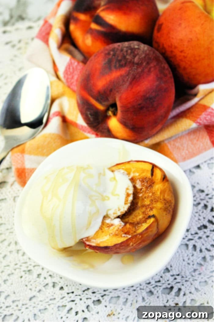 Perfect Air Fryer Peaches 9 Two halves of air fried peaches, topped with a dollop of whipped cream, on a white plate with a fork.