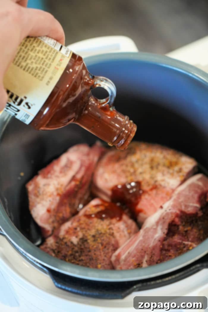 Instant Pot Pulled Pork 6 Pouring barbecue sauce over seasoned pork butt in an Instant Pot.