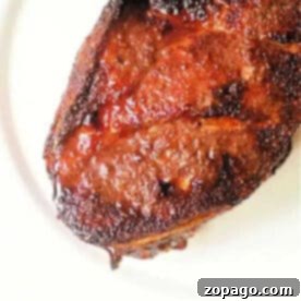 Crispy Air Fryer Pork Roast 6 Close-up of a cooked, well-seasoned steak with a crispy, caramelized crust on a white plate, reminiscent of the perfect finish an air fryer pork roast offers.