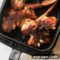 Crispy Air Fryer Turkey Wings 6 Close-up of grilled turkey wings inside an air fryer basket.
