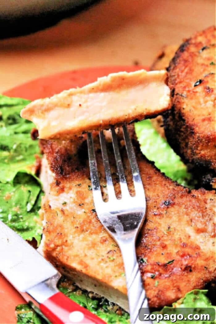 Crispy Air Fryer Pork Chops 10 Two perfectly cooked bone-in pork chops in an air fryer basket, with a meat thermometer indicating the ideal internal temperature.