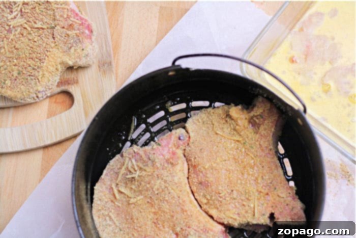 Crispy Air Fryer Pork Chops 6 A freshly breaded pork chop, perfectly prepared for air frying, promising a crispy and flavorful meal.