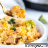 Lifting a forkful of delicious Instant Pot cheesy chicken and rice with broccoli from the bowl.