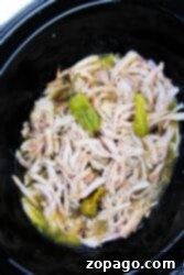 Tangy Pepperoncini Chicken 6 Pepperoncini chicken with shredded peppers simmers perfectly in a black slow cooker.