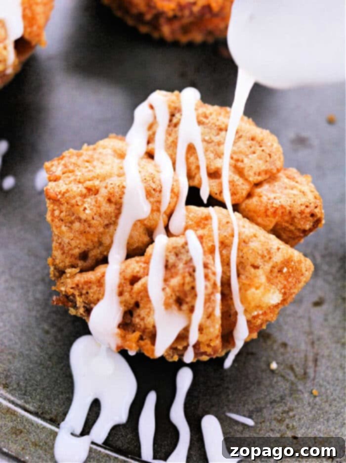 Biscuit Monkey Bread Muffins 2 Golden brown monkey bread muffins made from refrigerated biscuits, stacked on a cooling rack, glistening with glaze.