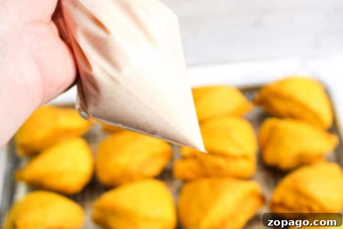 Freshly baked pumpkin scones on a cooling rack, generously drizzled with a sweet glaze, ready to be served.