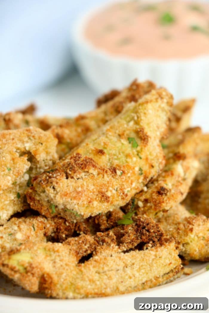 Crispy Air Fried Artichoke Hearts 5 Close-up of crispy breaded artichoke hearts with a hint of air fryer artichoke hearts, accompanied by a small bowl of dipping sauce in the background.