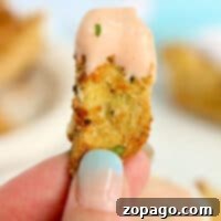 Close-up of a hand holding a breaded perfectly cooked air fryer artichoke hearts.