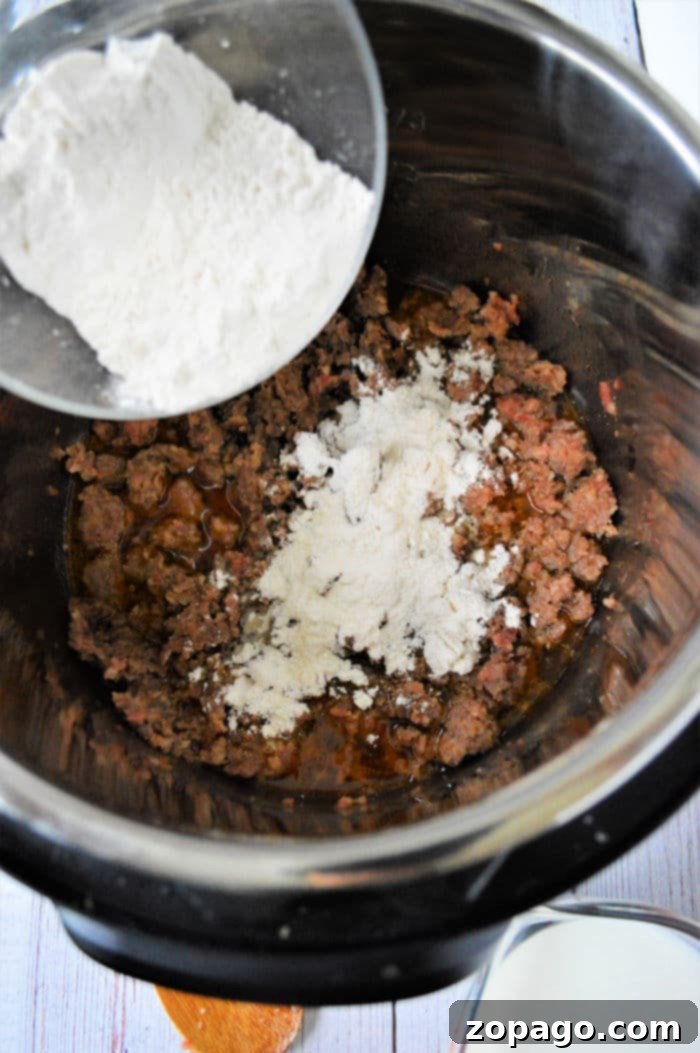 Easy Instant Pot Sausage Gravy 6 Sausage gravy being stirred in an Instant Pot after pressure cooking, showcasing its creamy texture.