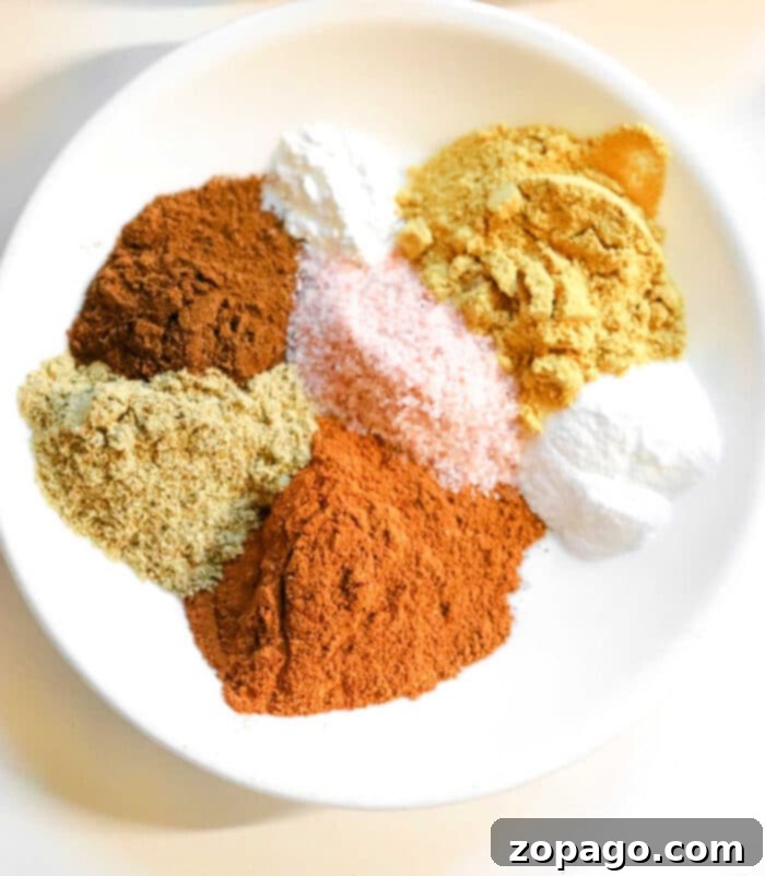 Assortment of gingerbread spices, including cinnamon, ginger, cloves, nutmeg, allspice, and cardamom, ready for mixing.