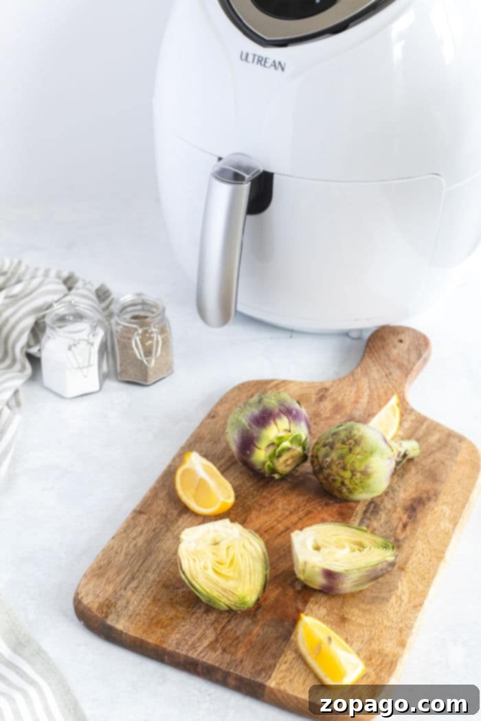 Artichokes and lemon slices rest elegantly on a wooden board, accompanied by an air fryer artichoke creation and various spice jars.