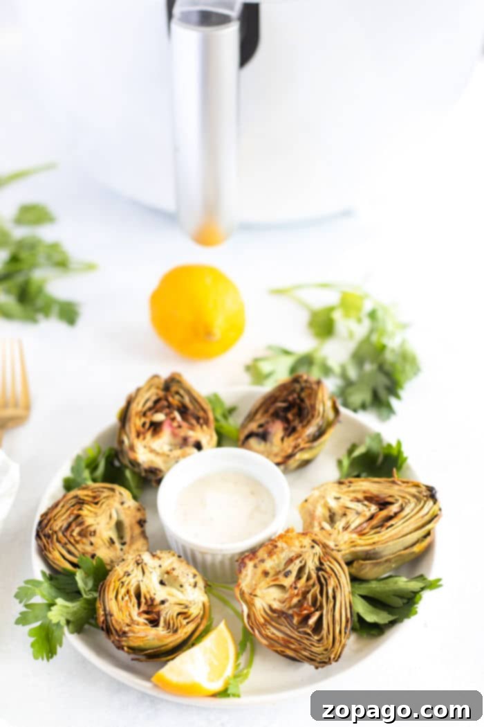 Air Fryer Artichokes on a serving plate with dip