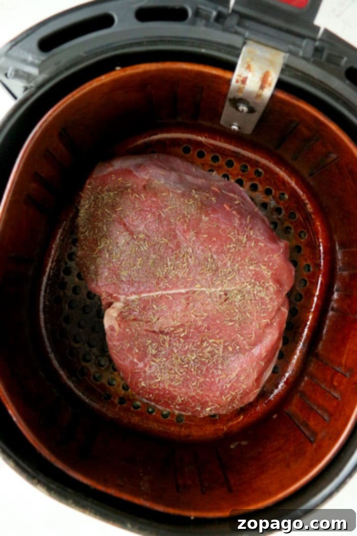 Succulent Air Fryer Rump Roast 5 A close-up of a perfectly seasoned rump roast in an air fryer basket, ready to cook.