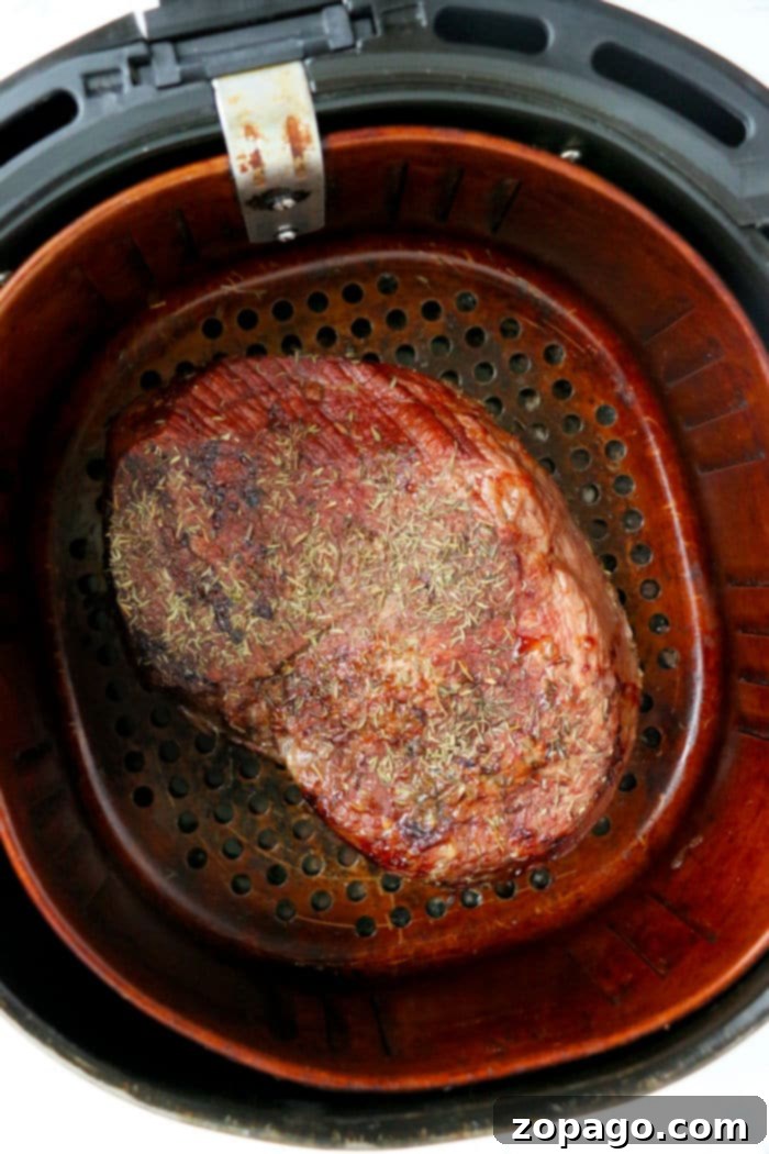 Succulent Air Fryer Rump Roast 6 A delicious air fryer rump roast sliced and served on a plate with fresh herbs.